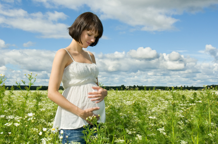 Une femme heureuse qui se touche le ventre et qui va consulter un ostéopathe